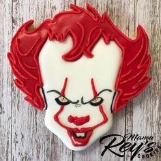 a close up of a cookie on a wooden surface with the face of a clown