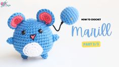 a hand holding a small blue crocheted mouse with two ears on it's head