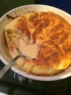 a white bowl filled with food sitting on top of a stove next to a spatula