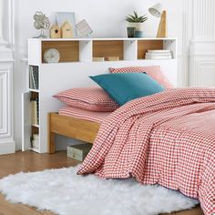 a bed with red and white checkered sheets, pillows and blankets on top of it