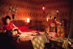 two children are laying on a bed in a room with red walls and patterned wallpaper