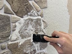 a person is painting a brick wall with white and gray paint on the walls, while holding a black brush