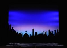 the stage is lit up with purple and blue lights in front of silhouettes of buildings