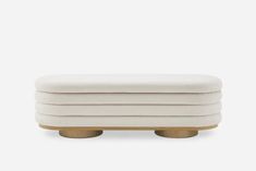 a white ottoman with gold legs