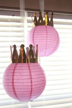 two pink paper lanterns hanging from the ceiling in front of a window with white blinds