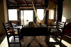 a dining room table with two chairs and a hammock hanging from the ceiling