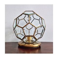 a glass and brass vase sitting on top of a wooden table