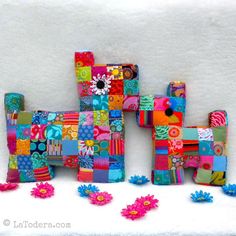 three colorful pieces of art sitting on top of a snow covered ground next to flowers