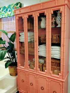 an orange china cabinet with baskets and towels