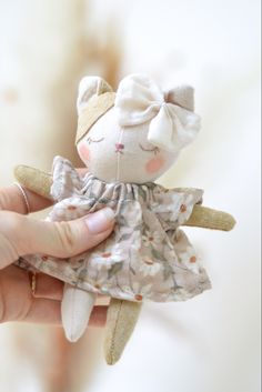 a hand holding a small stuffed animal in a dress