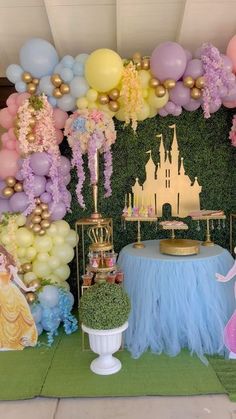 a table topped with cake and balloons next to a wall covered in fairy land decorations