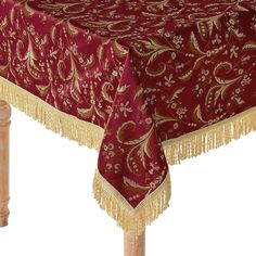 a red table cloth with gold fringes and flowers on it, sitting on top of a wooden stand