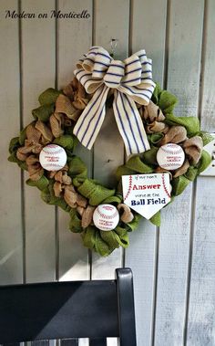 a wreath with baseballs on it hanging from the side of a wall next to a chair