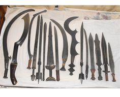 an assortment of knives are displayed on a white cloth covered tablecloth in a box