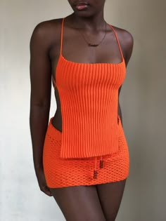 a woman in an orange knitted swimsuit poses for the camera with her hand on her hip