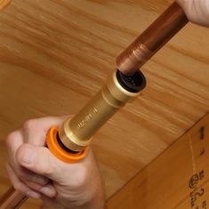 a person holding an orange and black object in their hand on top of a wooden table