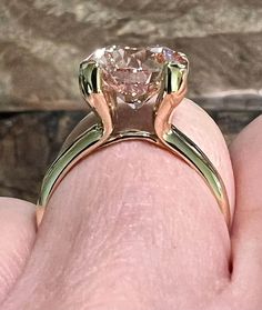 a person's hand holding a ring with a large diamond in the center and two smaller diamonds on each side