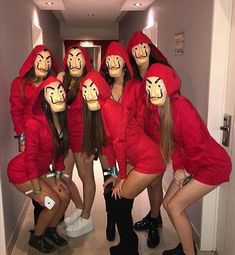 several women in red dresses and masks posing for a photo with their faces painted on them