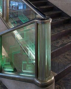 an escalator with green glass railings and stairs leading up to the second floor