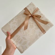 a person holding a wrapped present with a brown ribbon on it's wrapper