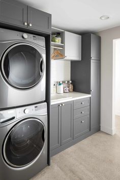 a washer and dryer in a small room with gray cabinets on the wall