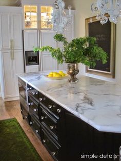 a kitchen island with marble counter tops and cabinets in the background, surrounded by green rugs