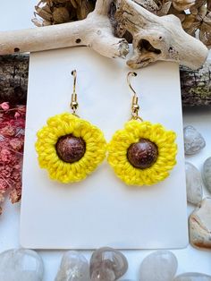 a pair of yellow and brown earrings sitting on top of a white piece of paper