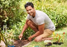 a man kneeling down to plant some plants in the grass and smiling at the camera