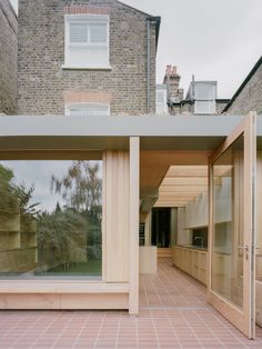 an open air kitchen and living room in front of a brick building with large windows