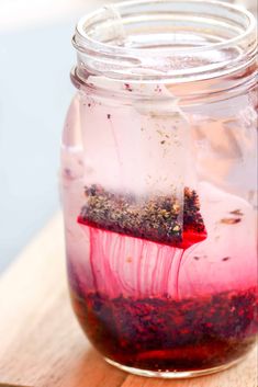 a jar filled with red liquid sitting on top of a wooden table