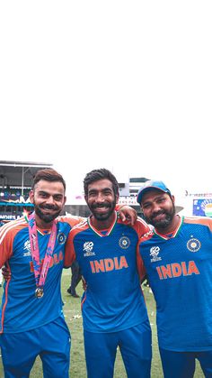 three men standing next to each other wearing blue and orange uniforms with medals around their necks