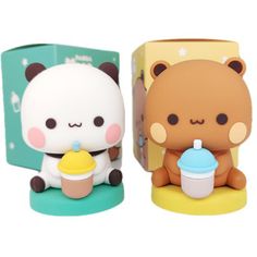 two small figurines sitting next to each other in front of a box with a bear holding a cup