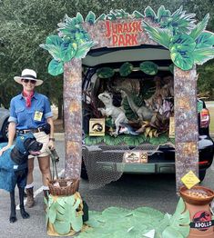 a woman standing in front of a truck decorated with fake dinosaurs and other things on display