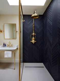 a bathroom with a gold faucet next to a white sink and shower head