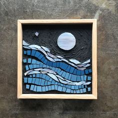 a wooden frame with blue and white mosaics on the wall next to a moon