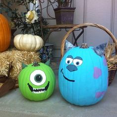 two pumpkins with faces painted on them sitting in front of a basket filled with hay