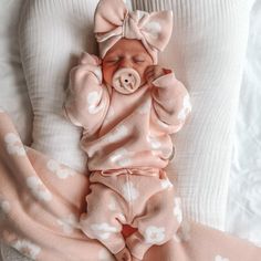 a baby is laying on its back in a pink outfit with white polka dots and a pig