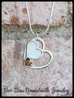 a heart shaped pendant with two hearts hanging from it's side on a stone wall