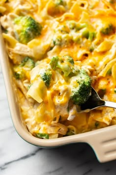 a casserole dish with broccoli and chicken in it is being held by a fork