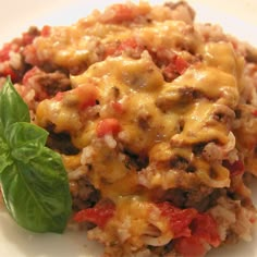 a close up of a plate of food with meat and cheese on it next to a green leaf