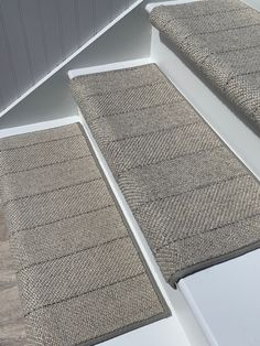 carpeted steps leading up to the top of a house with white walls and wood flooring