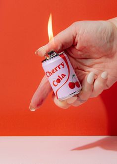 a person holding a lighter in their hand with the word cherry cola written on it