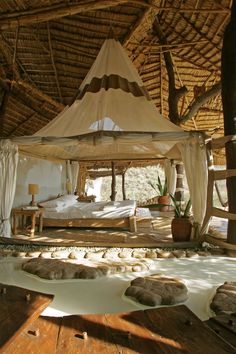 a canopy bed sitting in the middle of a room next to a table and chairs