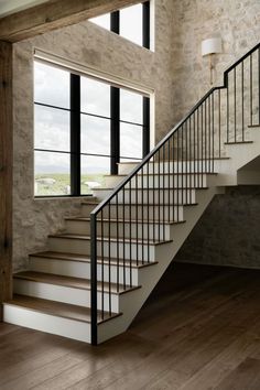 a stair case in front of a window next to a stone wall and wooden floor