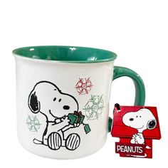 a coffee cup with a snoopy christmas design on it and a sticker next to it