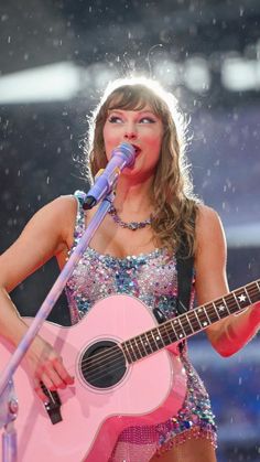 a woman singing into a microphone while holding a guitar