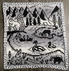 a black and white rug with an image of animals in the woods on it's side