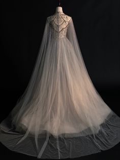 the back of a wedding dress on display in front of a black background with white lace and tulle