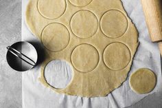 an uncooked pizza dough with circles on it and a rolling pin next to it