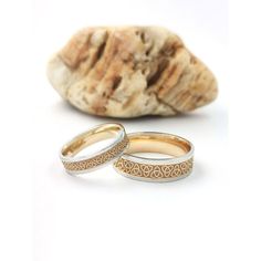 two wedding rings sitting next to a rock